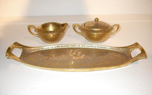 Gold plated ceramic sugar and creamer with tray in an enamel slip glaze with textured vegital decor.<br />
<br />
Mark shown, by Oscar & Edgar Gutherz Royal Austria