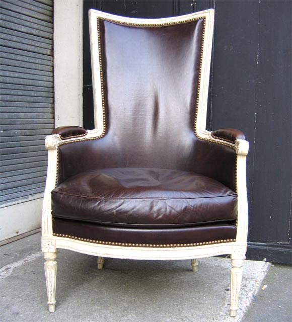 Louis XVI bergère in white patina wood with brown leather upholstery. High and narrow back-rest.