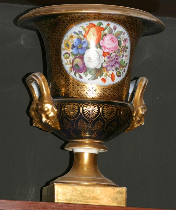 Una straordinaria coppia di urne Royal Worcester. Il corpo delle urne è di colore blu intenso con decorazioni dorate, manici, bordi e base dorati. La riserva sul fronte presenta fiori finemente dipinti, mentre la riserva sul retro presenta trofei