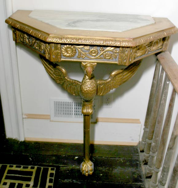 A pair of impressive giltwood and painted monoped console tables with inset marble tops. The half octagonal tops have a deeply molded edge with inset grey and white marble. The apron has deeply carved gilded decoration on a painted background and is