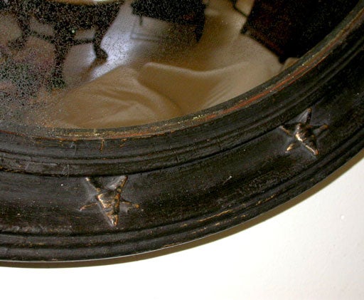 Ebonized round frame with raised star motif and convex mercury mirror.