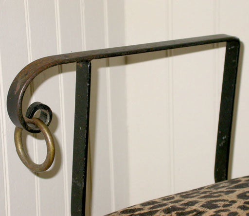 Folding iron bench featuring brass swan head detail and faux leopard upholstered seat.