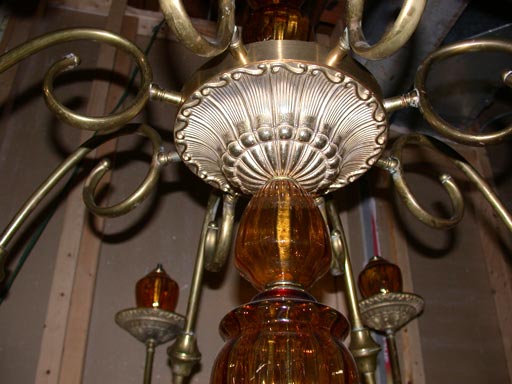 This eight arm chandelier is an original Brunelli Design which uses brass components from the 1940's and amber colored Murano glass.