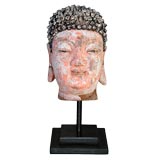 A SERENE CHINESE POLYCHROMED STUCCO HEAD OF BUDDHA