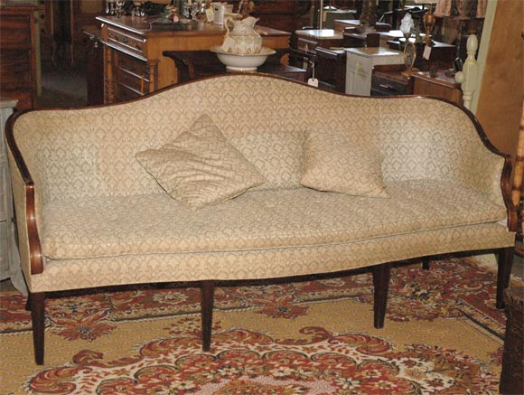 This Hepplewhite style sofa with its camel back and sweeping arms is upholstered in Fotuny (smoke stained) fabric. The sofa stands on eight tapered legs. Jefferson West antiques offer a large variety of interesting antique furniture, lighting