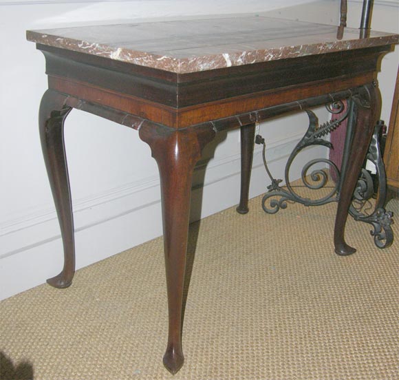 Early 18th C Queen Anne red walnut marble top table, the later top over heavily molded apron over cabriole legs.