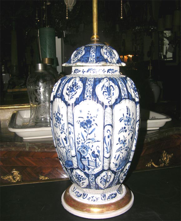 A pair of Dutch ribbed vases with traditional blue decoration on a white ground with foo dog finials.  Now mounted as lamps on turned wooden bases with gilt edges.