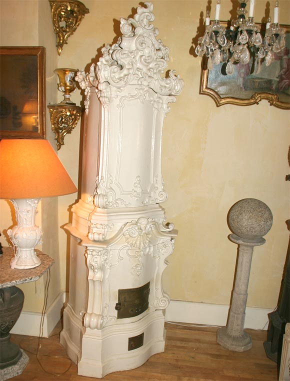 A white glazed faiance heating stove of arcitectural form decorated throughout with rococo decoration and surmounted with an elaborate top