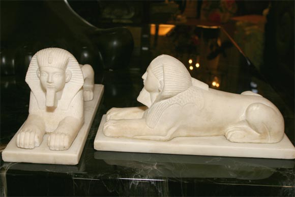 A pair of carved white marble sphinx's on bases of the same material.