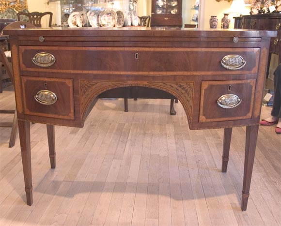With a fine chestnut-colored patina, detailed with intricate marquetry and inlay, this bowfront Dressing Table is an exemplary piece from the Sheraton and Hepplewhite-influenced 1790's. The table surface exhibits a beautiful 