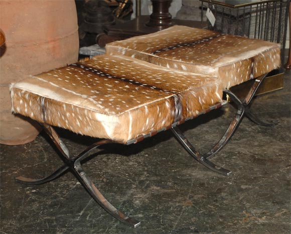 Two Barcelona-style footstools or ottomans of chrome plated steel. These are a matched pair, but we will sell them separately.  We believe these are covered in dama dama (fallow deer) hide.  The price below is per footstool.