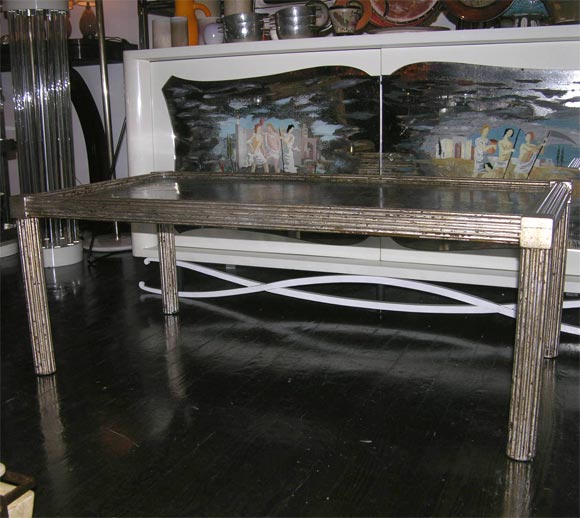 Rectangular coffee table; the incised metal top depicting classical scenes, patinated bronze, the legs and outer frame silvered. By Laverne, American 1950s.<br />
46