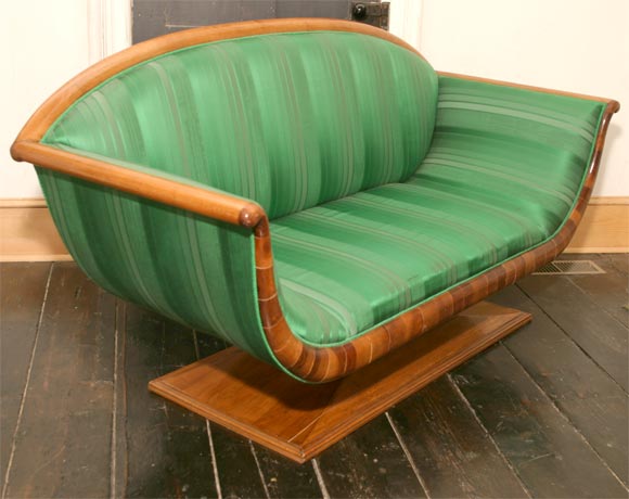 An Austrian Biedermeier style small pedestal sofa in fruitwood represents the high point in this design form. Amazing in its day the style is sleek and dramatic and still is to this day. The Fine grained wood choice is made all the more interesting
