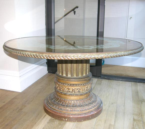 A round French low side table with carved and giltwood base having Neo-classical details and rope shaped with inset reverse glass decorated and gilt top.