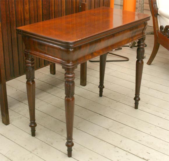 Late 19th century card table in nicely figured mahogany with turned and carved legs, the top turns and opens to a square.   Can be used as a console table or card table.