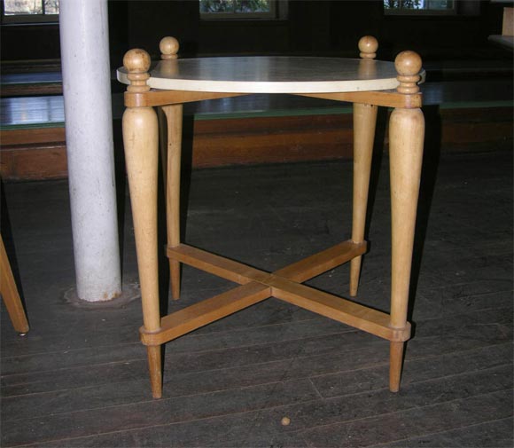Petite table ronde à plateau parcheminé et cadre en bois blond.