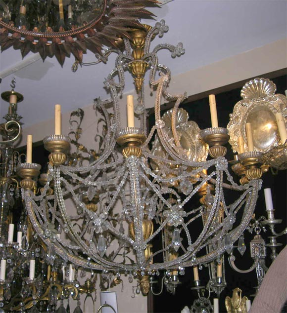 A large circa 1920s ten-arm giltwood Italian chandelier with beaded body and crystal flowers details and pendants.

Measurements:
Height 54?
Diameter 42?.