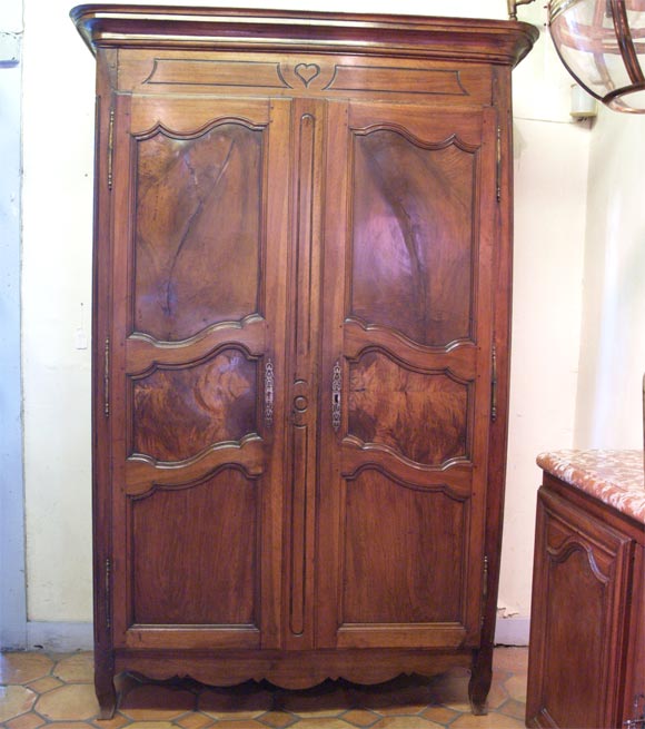 Early 19th century French walnut armoire in the Louis XVI taste, with scalloped skirt and interior band of drawers, carved heart decoration.