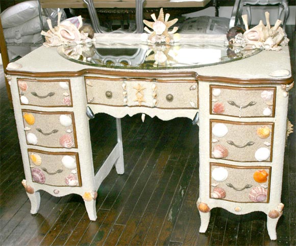 This  shell and sand encrusted vanity with dramtic eglomes mirrored top and shell and sea life designs is a one of a kind custom created peice of furniture.. The sides also mirrored has large  star fish applied to  the sides. All across the top at