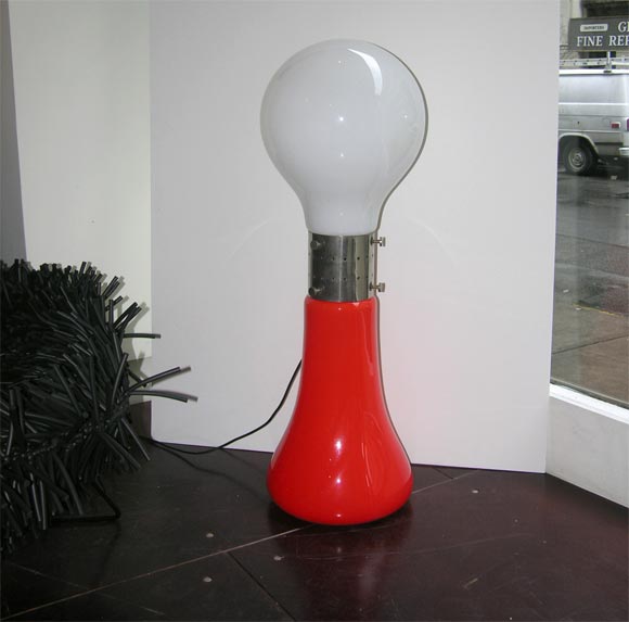 This attractive floor was manufactured by Mazzega in 1969. The orange glass base is topped off with a white light bulb shaped top. They are connected with a brushed aluminum collar. Both bottom and top of this lamp light up to a very warm and