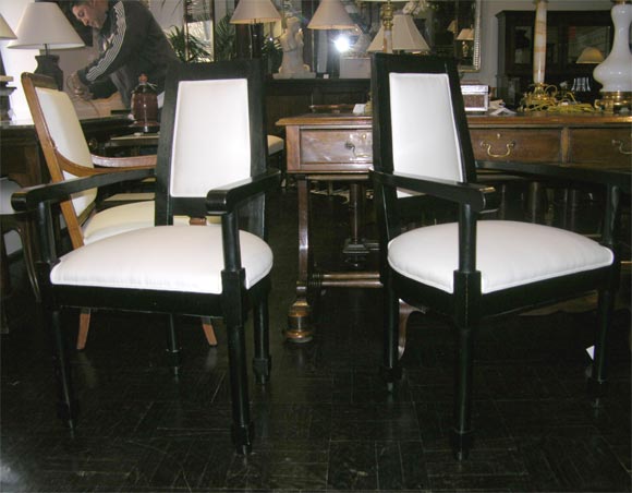 Pair of early 20th century ebonized fauteuils. Shaped, downswept arms, square tapered legs joined by stretchers with vertical supports.