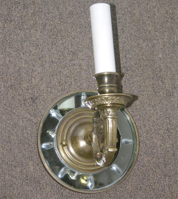 a pair of mirrored sconces with brass brackets