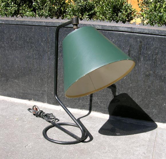 Desk lamp  of bent and curved tubular steel with adjustable visor.