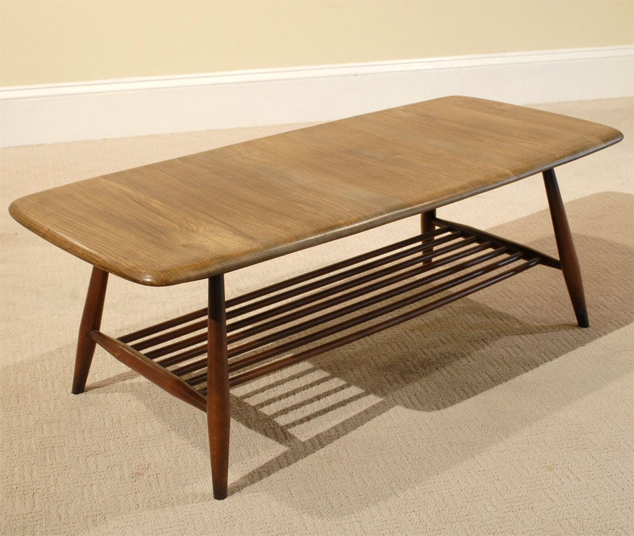Modernist Ercol teak cocktail table with lower spindle shelf and round tapered legs.  Early Ercol furniture from the 1950s has been prized in the U.K. since top fashion designer Margaret Howell began showcasing it as an extension of her designs for