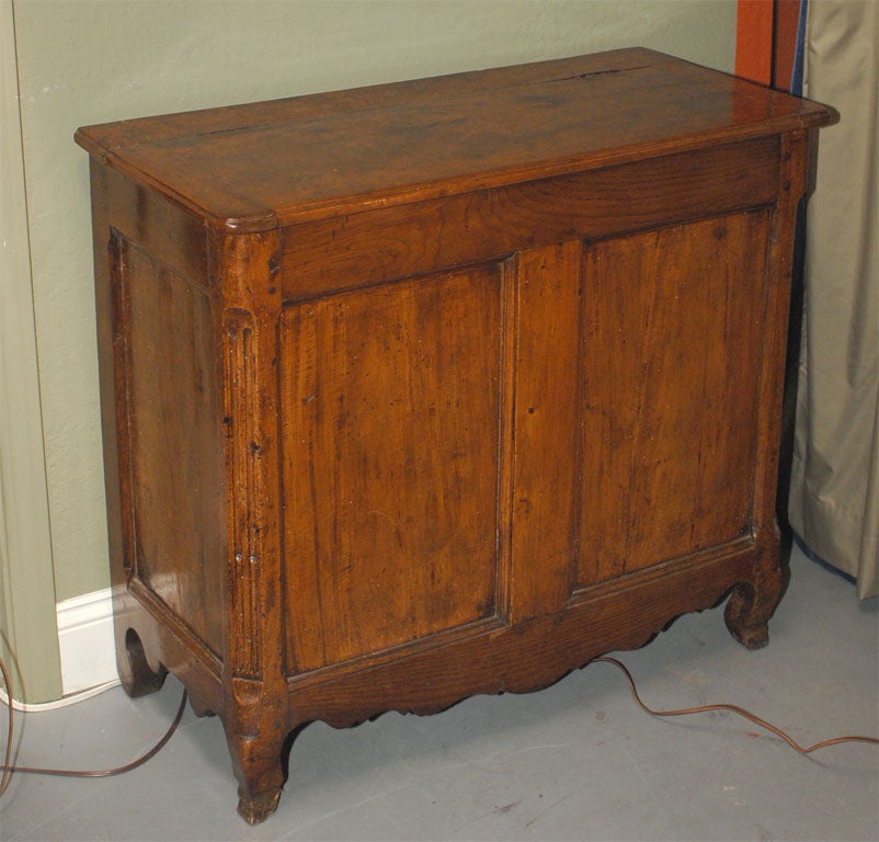 With a rectangular hinged top opening to the inside, above a two-panelled front, flanked by fluted corners, atop a shaped apron and serpentine feet.