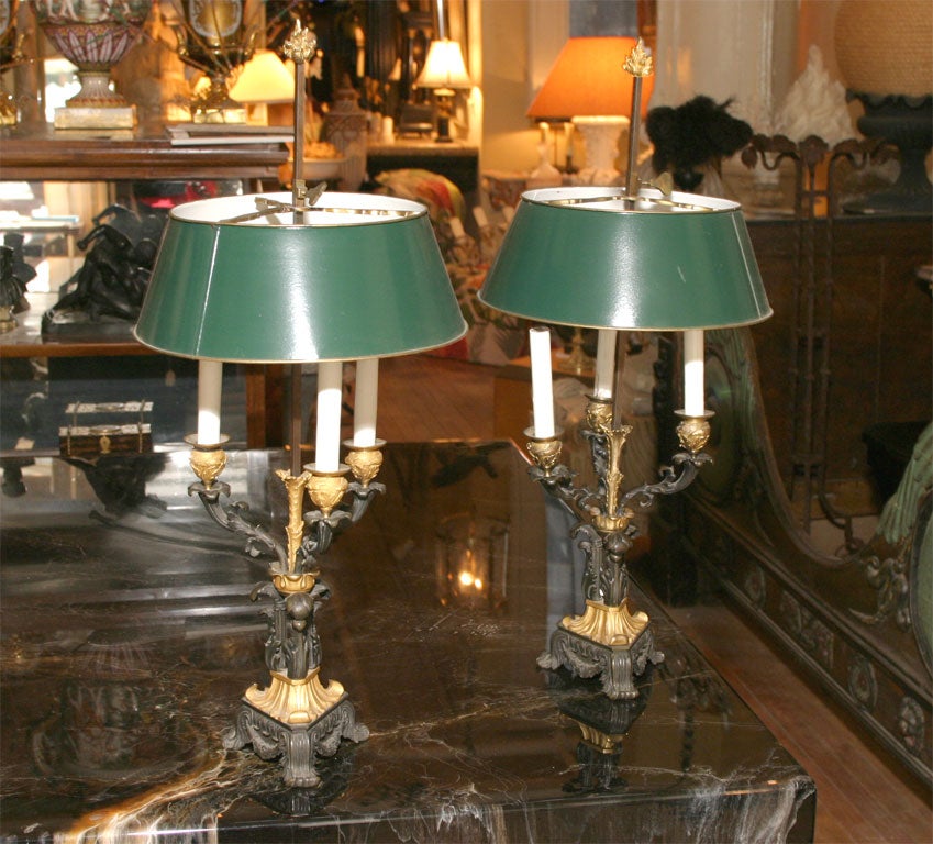 Une très belle paire de lampes de table Louis Phillipe à trois bras en bronze doré et patiné, conservant leurs abat-jour originaux en métal tolé.