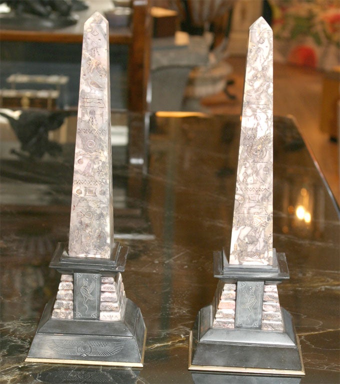 A pair of marble and slate obelisk designed as mantle garnitures with insized egyptian imagery