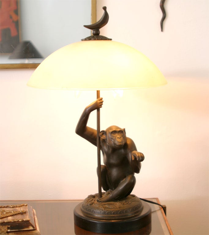 BRONZE MONKEY LAMP WITH ORIGINAL GLASS SHADE AND BRONZE FINIAL ON A WOOD BASE