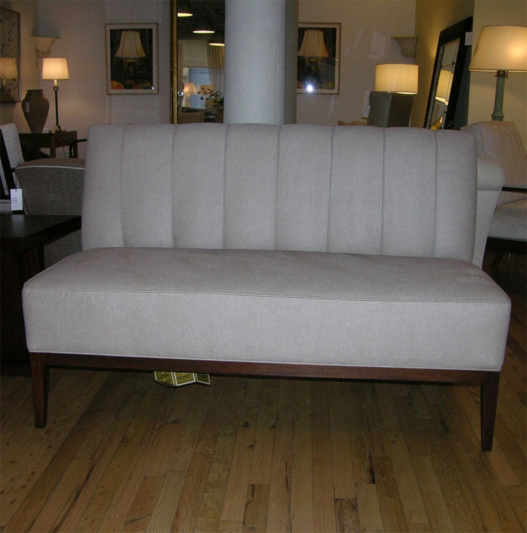 Upholstered armless loveseat with tapered dark wooden legs.  Designed by Mariette Himes Gomez for Hickory Chair.