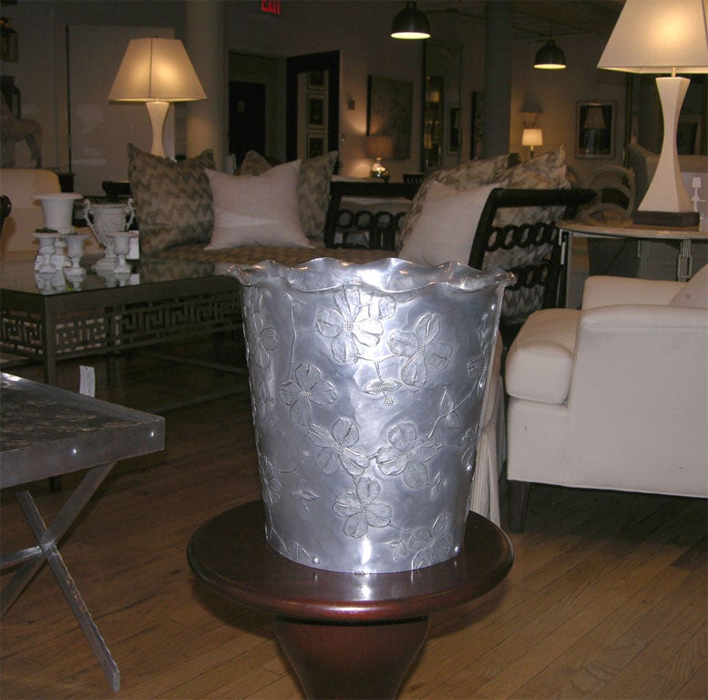 Aluminum wastebasket by the Wendell August Forge featuring hand hammered repousse flowers and scalloped top.  See matching table listed separately.