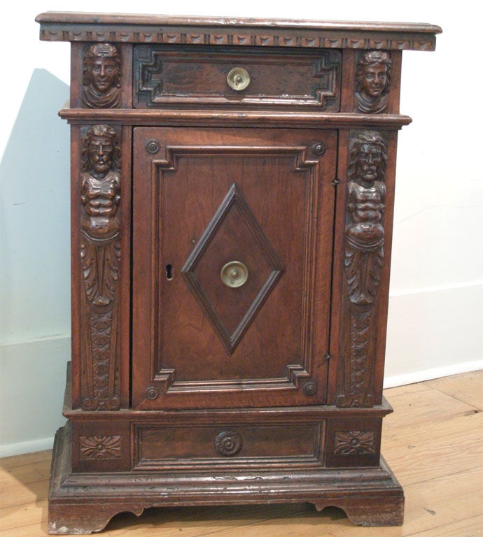 Small 18th c Italian walnut one drawer, one door cabinet with monopodial figures and diamond patterns.