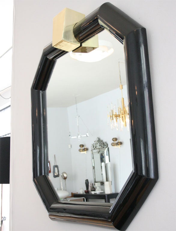 Mirror of black lacquered wood, with bold brass accent. Graphic, glamorous, 1970s high style.