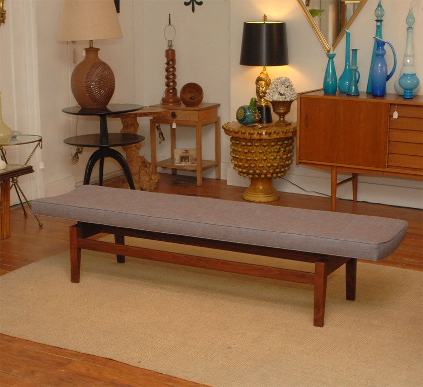 Jens Risom designed bench with a floating arched seat on a solid black walnut base.