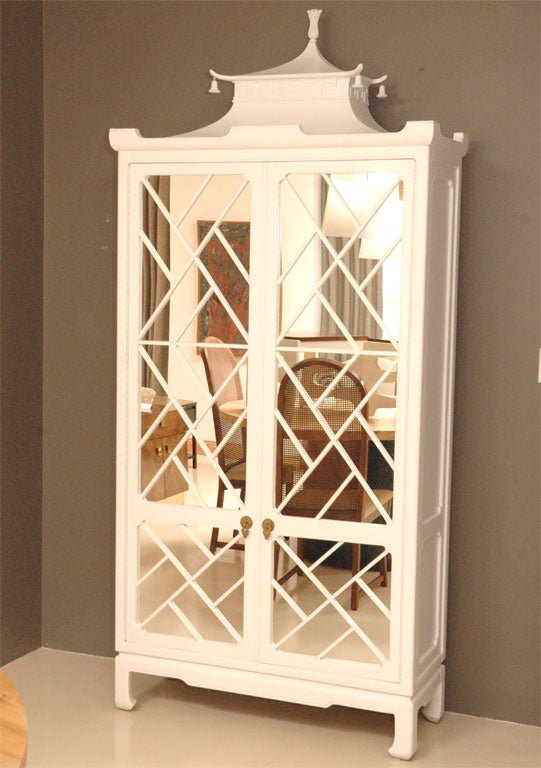 White lacquered chippendale cabinet with mirrored doors and asian style pagoda capped.  Interior holds plenty of storage space.
