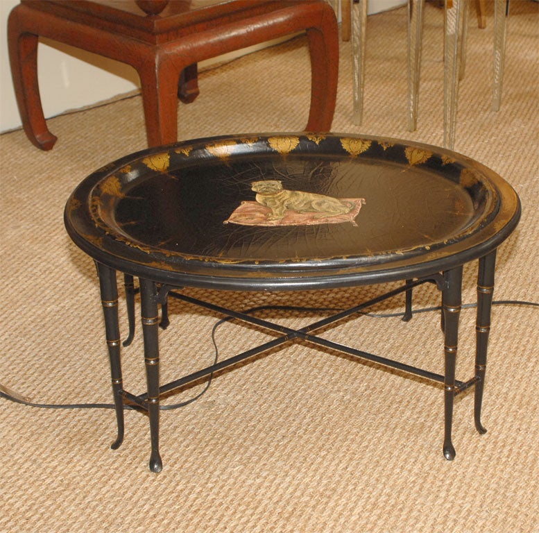 Regency papier mache tray-top cocktail table<br />
England, circa 1850<br />
The papier mache top having hand-painted picture of bulldog sitting on pillow with tassle corners, the outer edge with decorative gilt border, resting on oval, eight-leg