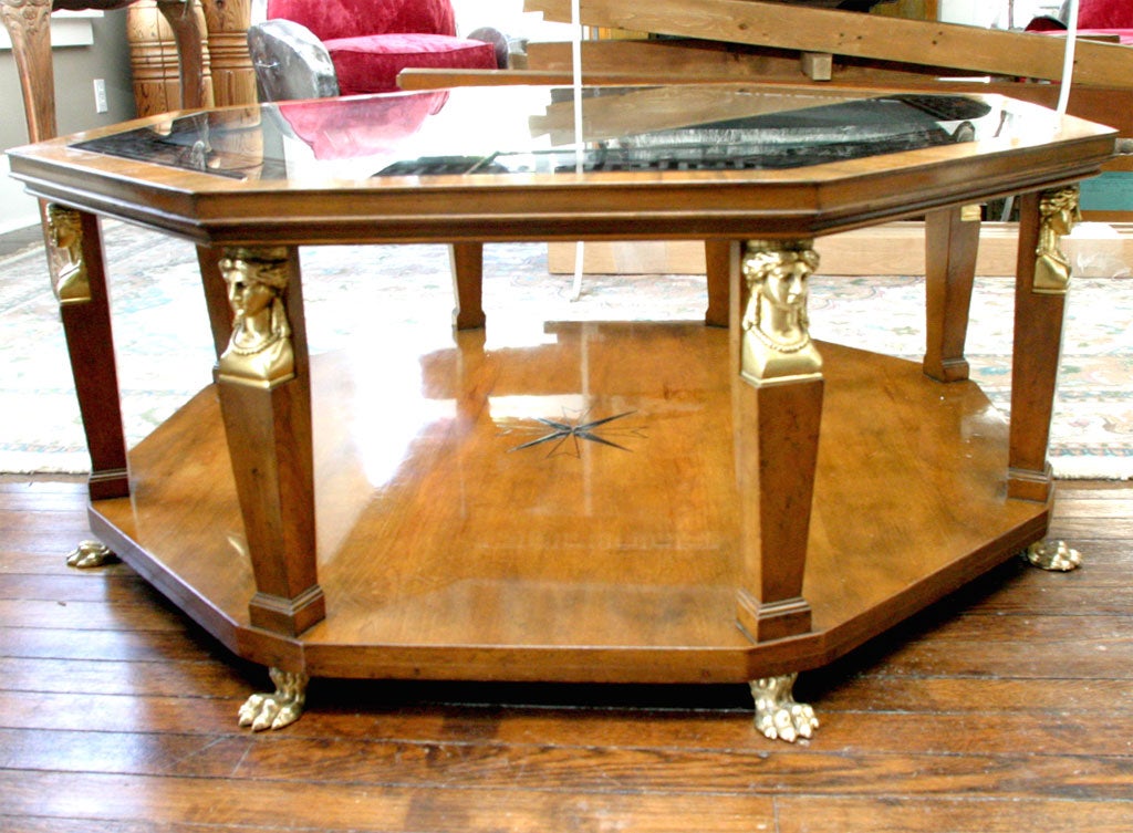 A large ocatagonal neo-classic coffee table in the empire style.The wood is fruit wood with paint decorated  centeral design and eglomaise greek key design on the glass top. All uprights mounted with egyptian style heads and ternimating in hairy paw