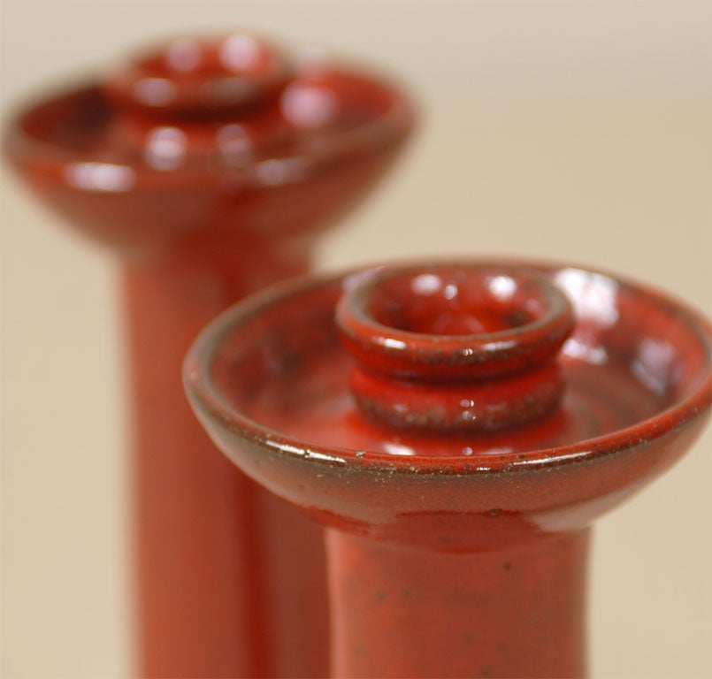 A pair of glazed red candlesticks by Neolia Cole, of Cole Pottery, North Carolina.  Signed and dated on the bottom.