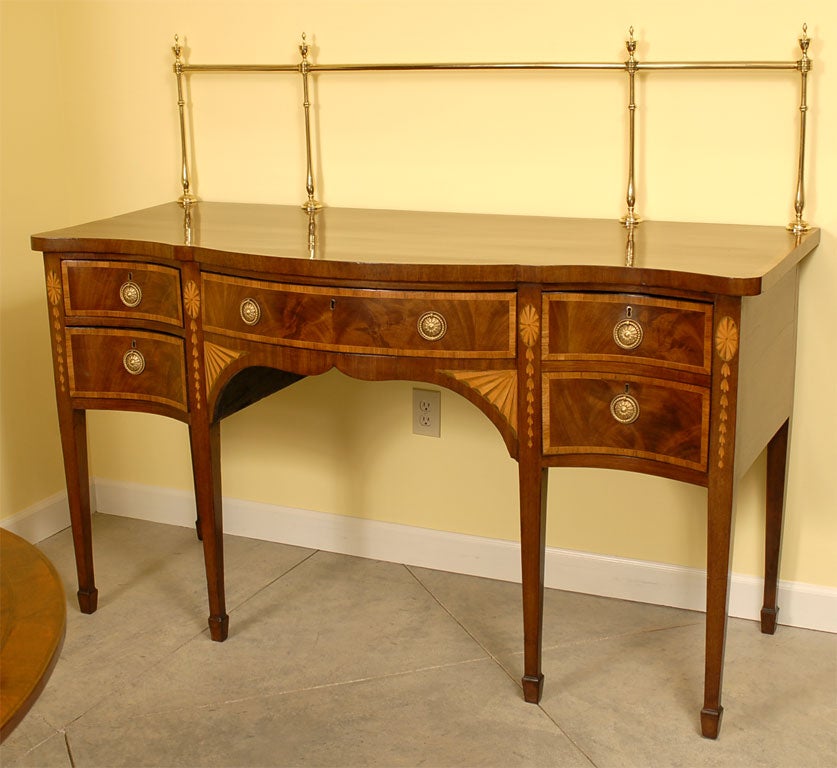 Late 18th century serpentine mahogany sideboard inlaid with tulipwood crossbanding, resting on six tapered legs with spade feet.