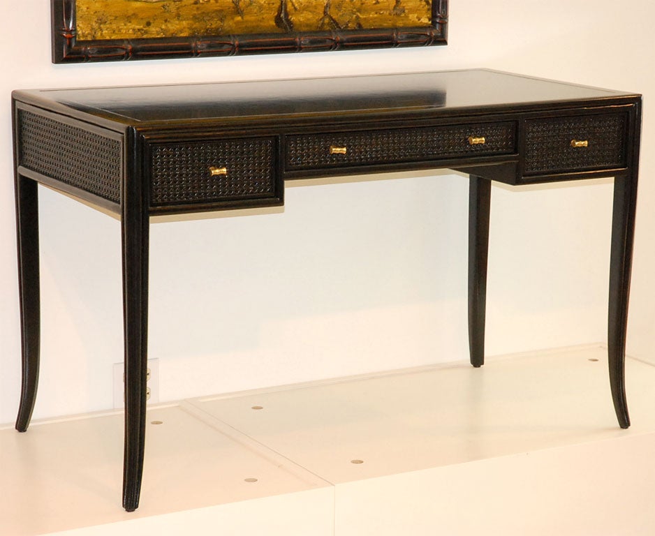 Black lacquered desk by Maguire Furniture.  Frame and drawers are caned and then lacquered.  It maintains the original faux-brass bamboo hardware.