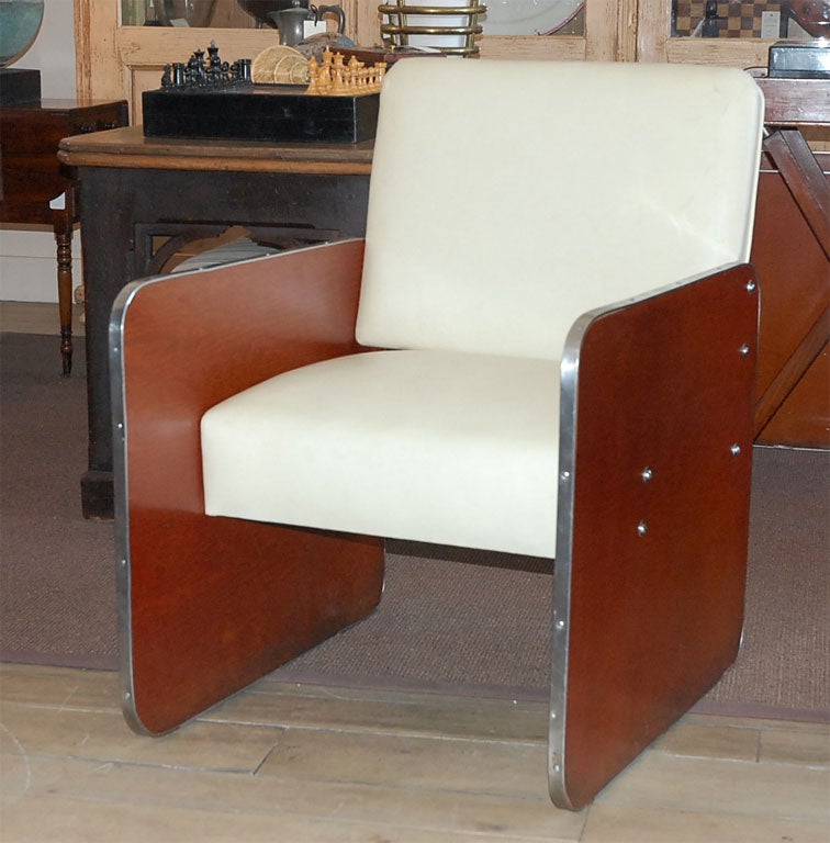A glamourous pair of modern art deco/ art moderne boat chairs. The square leather upholstered  backs and seats enclosed with square wood and curved metal  side panels