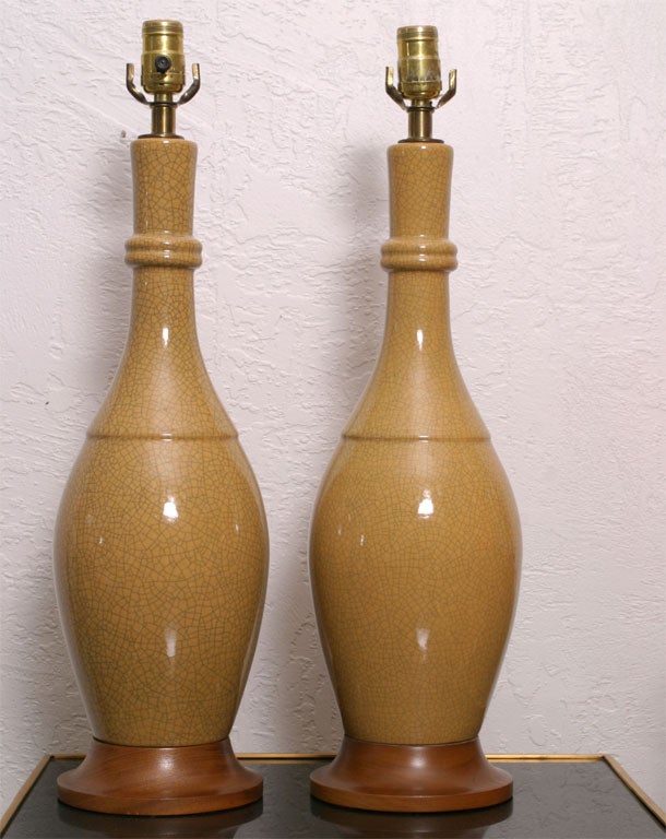 Pair of mustard yellow crackle glaze ceramic lamps.  Classic in shape these Mid- Century lamps have original wood bases.  They have not been rewired and should be for safety.