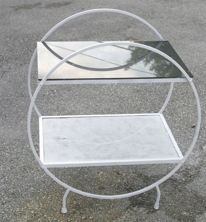 This Mid-Century Modern white enamel painted wrought iron outdoor bar cart with smoked glass top is perfect for your garden and outdoor entertaining. The glass top has been glued down. Buy this at this great rock bottom price now. It is from the