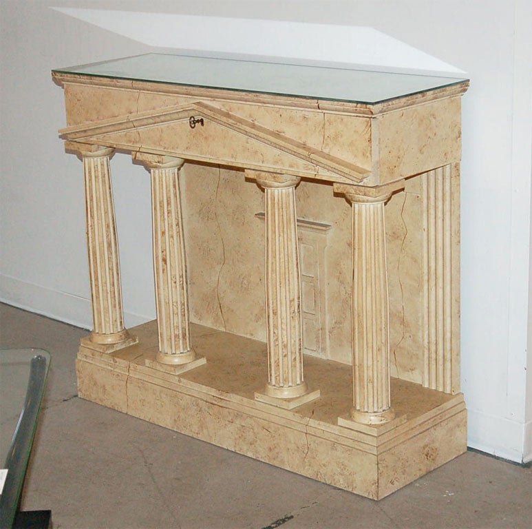 An illusionist console table in the form of a greek temple. Faux limestone painted carved wood table of four columns supporting a plinth drawer, backed with a 