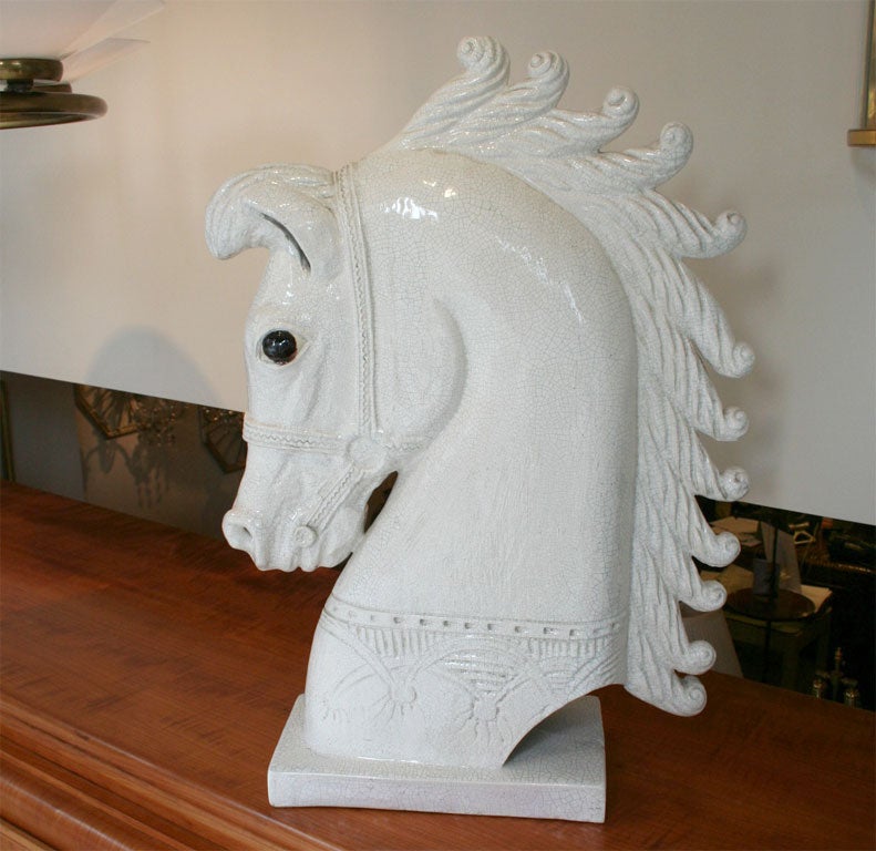 • An Italian ceramic lamp base in the form of a horses head with stylized mane bridle bit and harness on rectangular plinth and with white crackeleur glaze.