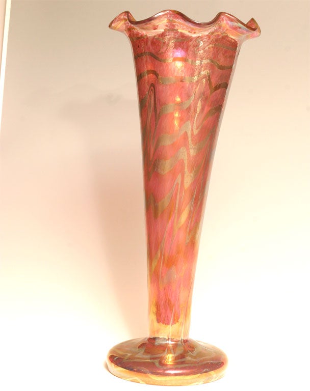 Il s'agit d'un vase monumental soufflé à la bouche, dramatique et impressionnant, fabriqué en Autriche. Il est décoré à l'intérieur de bobines d'or sur le grand corps en forme de trompette rose moucheté. L'iridescence subtile de l'ensemble en fait