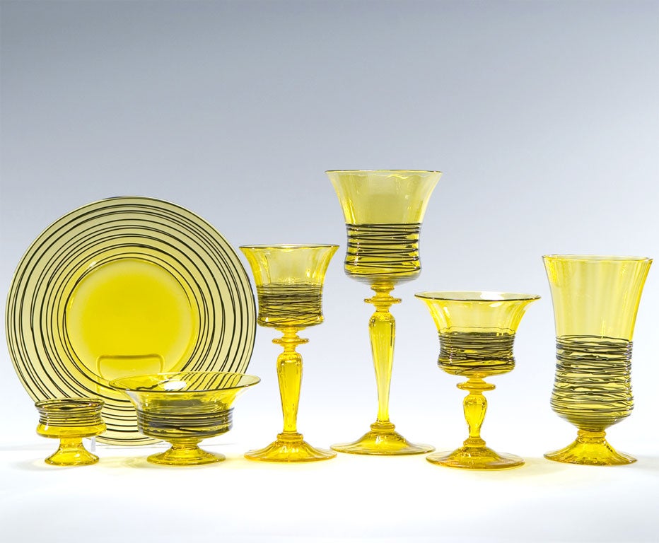 An extensive and outstanding Steuben handblown crystal stemware service for 12 with applied black threaded decoration. This amazing collection of Bristol yellow and black crystal includes 12 tall water goblets, 12 footed tumblers, 10 red wine